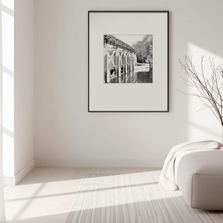 A black and white photograph in a frame hung on wall in a peaceful paler-coloured interior