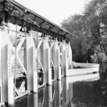 the large metal weir mechanism on the River Thames at Abingdon, reflected in the water on a still morning.